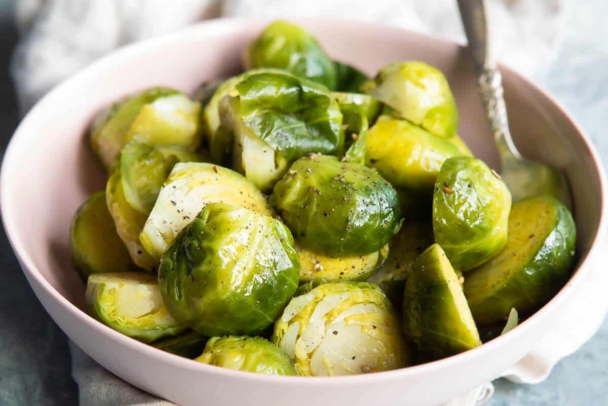 Steamed Brussels sprouts in a pink bowl.