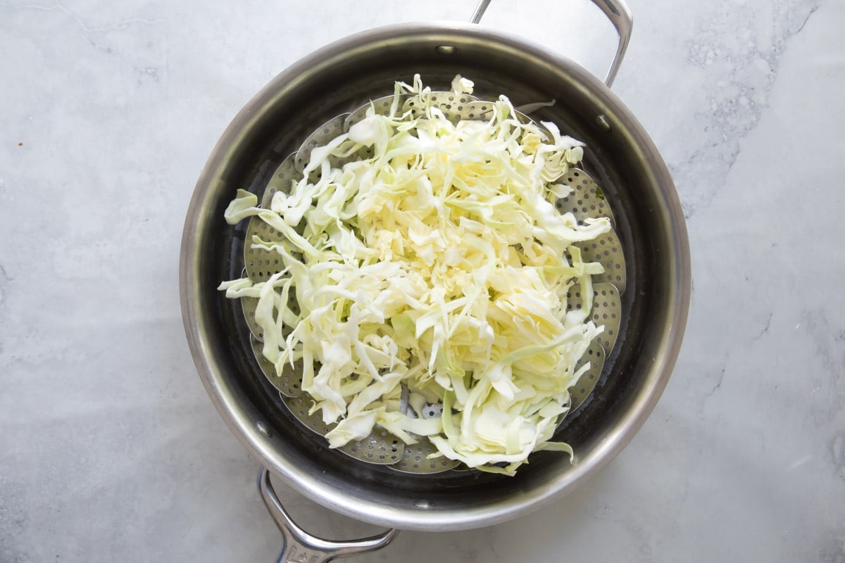 Raw cabbage in a steamer basket before being steamed.