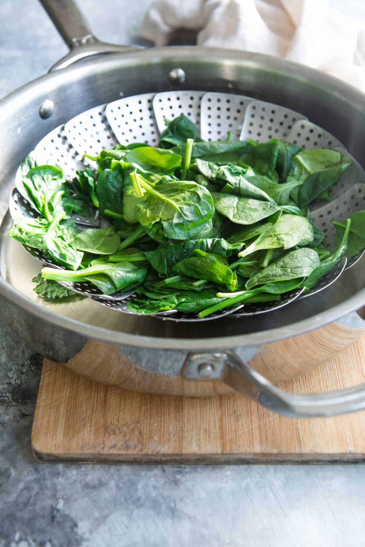 Spinach being steamed in a steamer basket.