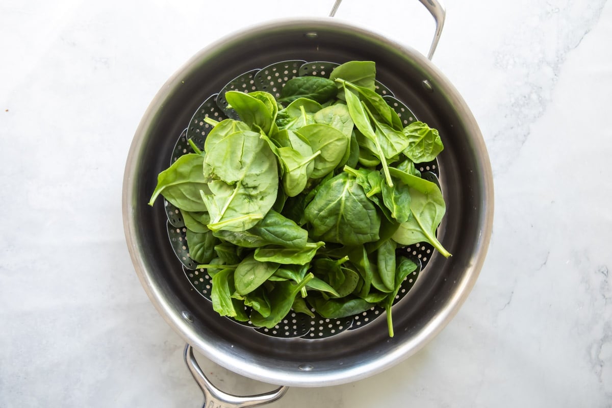 Raw spinach in a steamer basket before being steamed.