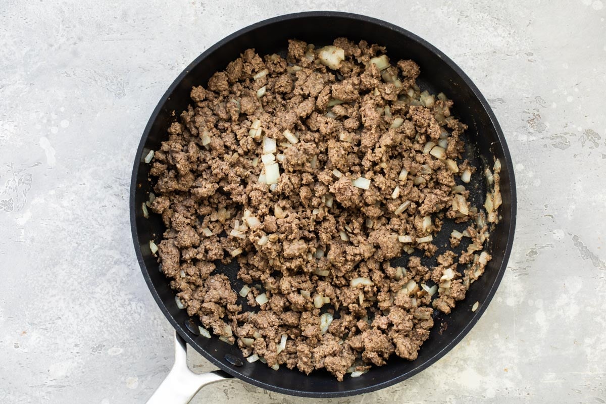 A skillet of ground beef and onions that has been browned.