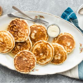 A platter of vegan pancakes with maple syrup on top.