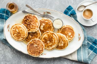A platter of vegan pancakes with maple syrup on top.