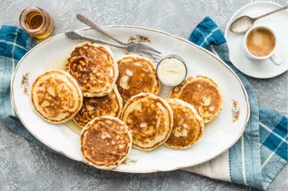 A platter of vegan pancakes with maple syrup on top.