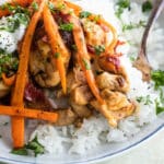 A white plate with Harissa chicken and rice.