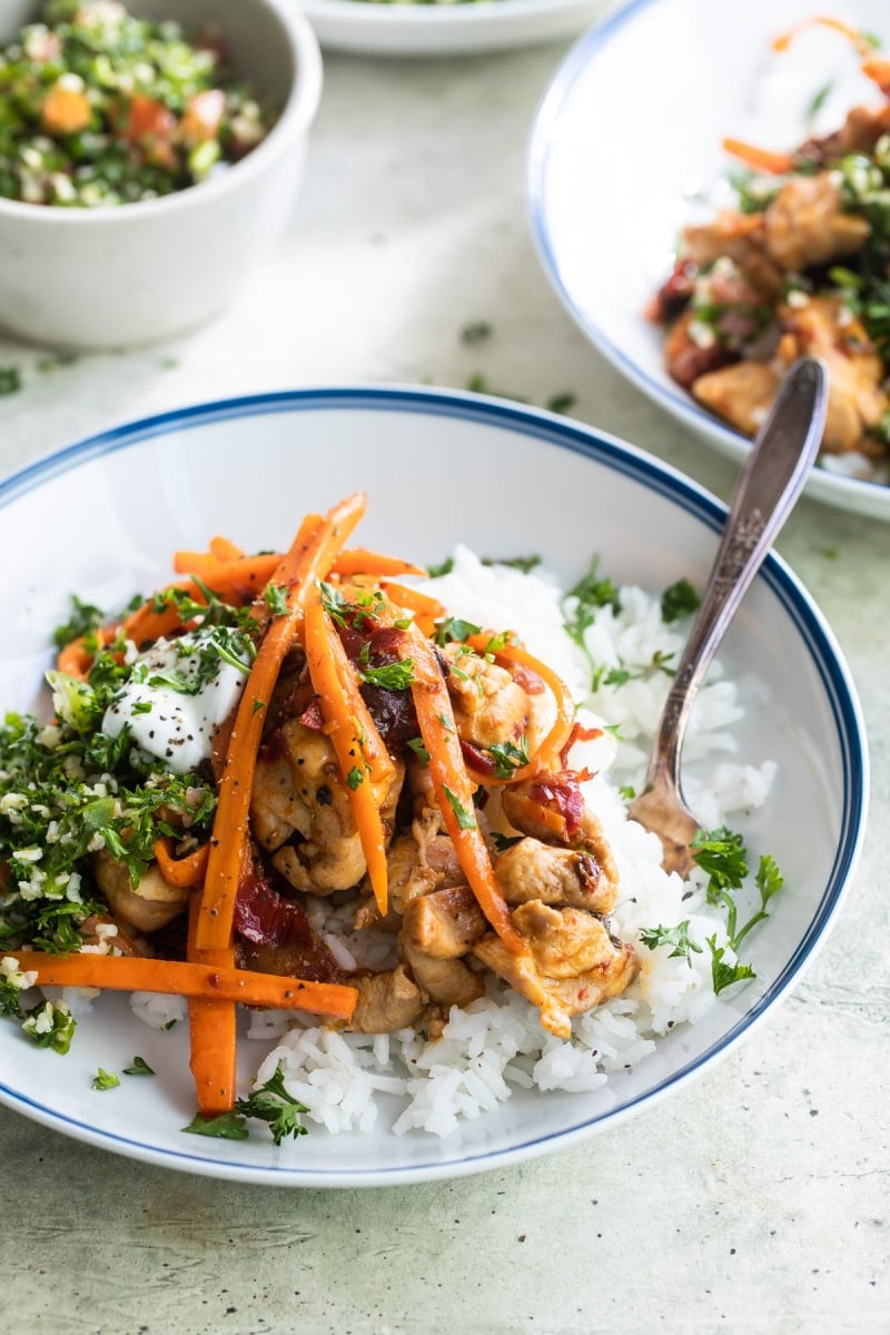 A white plate with Harissa chicken and rice.
