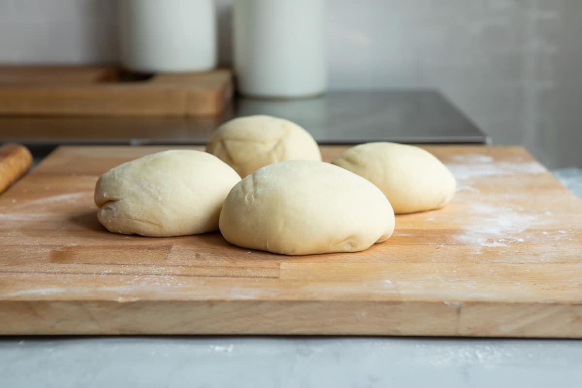 A ball of dough portioned into 4 pieces.