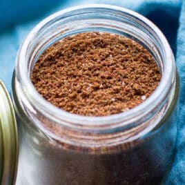 Taco seasoning in a glass jar with a blue napkin around it.