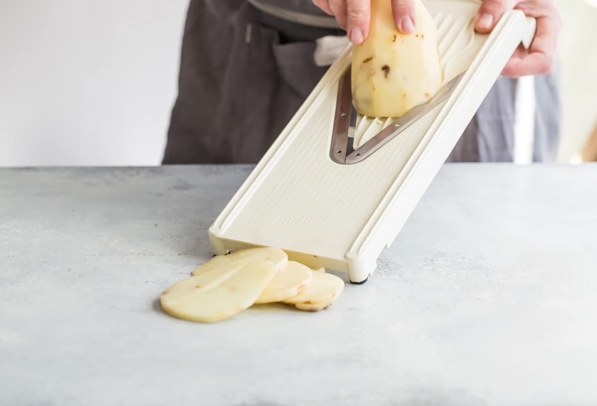 Slicing potatoes on a mandolin.
