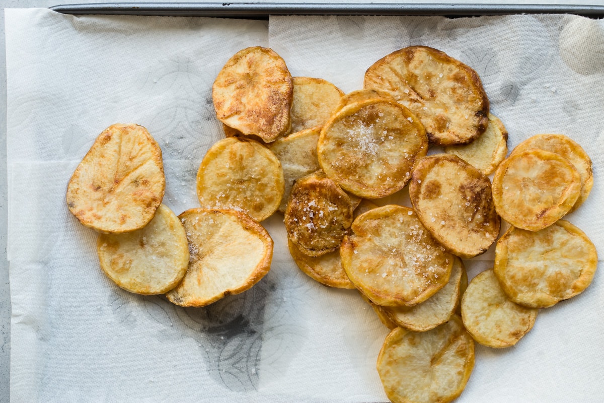 Fried potato slices draining on paper towels.