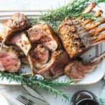 Roast rack of lamb on a white platter.