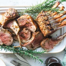 Roast rack of lamb on a white platter.