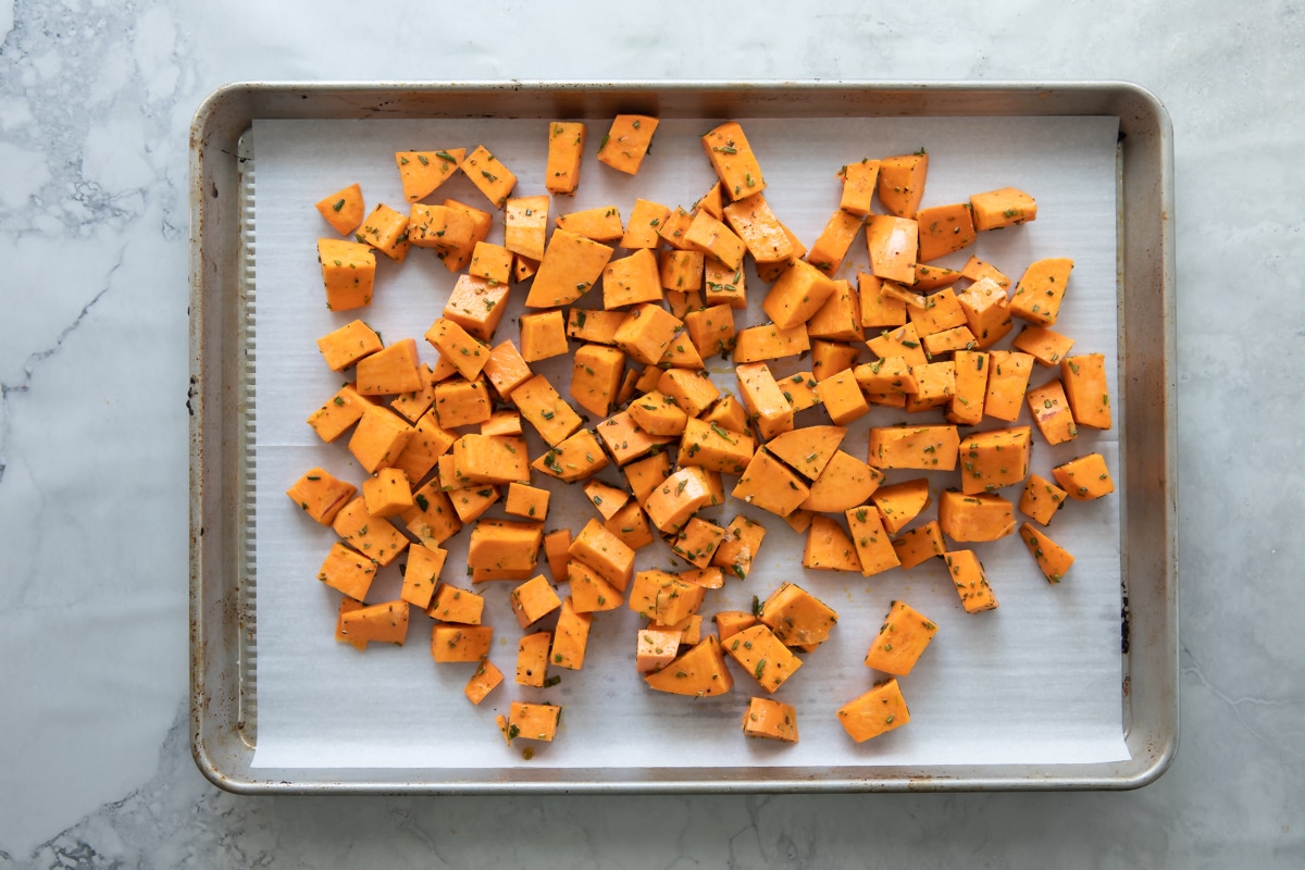A sheet pan of cubed raw sweet potatoes.