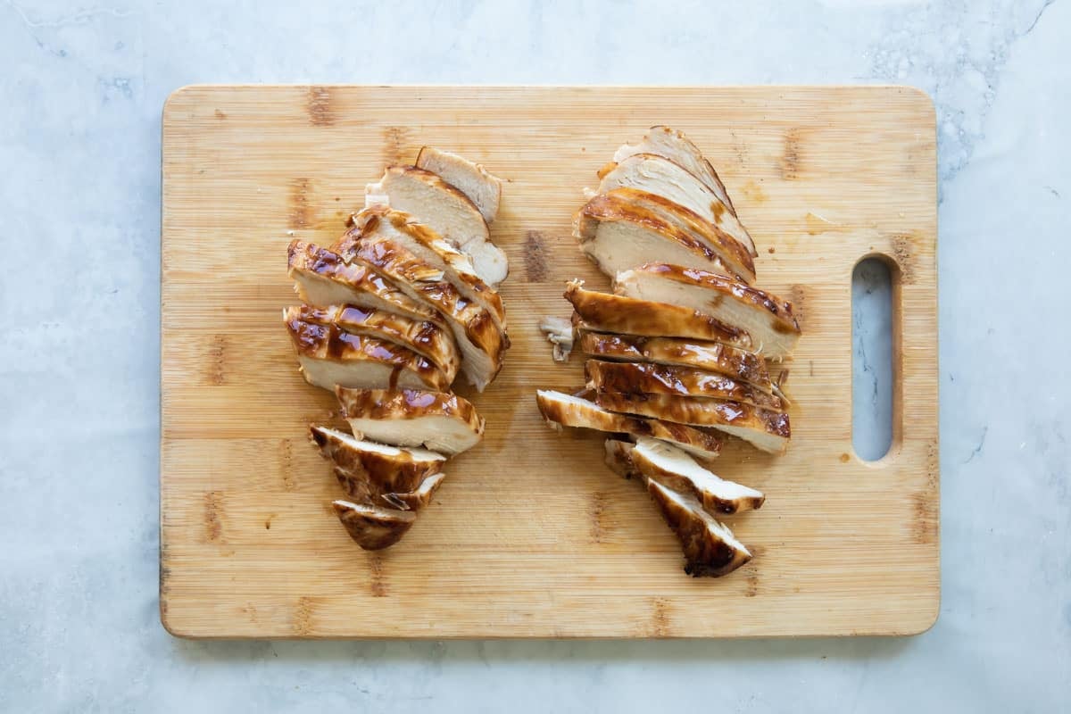 A cutting board with Teriyaki chicken.