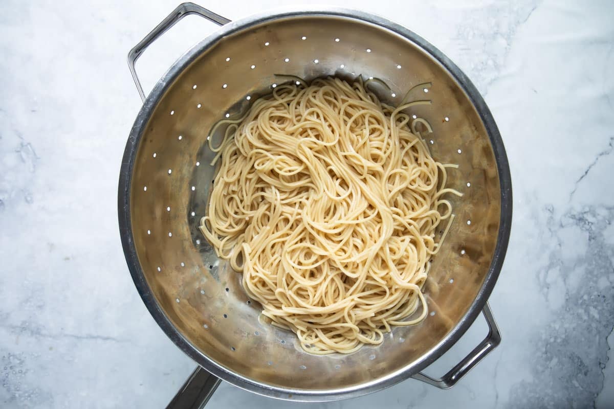 A colander full of cooked noodles.
