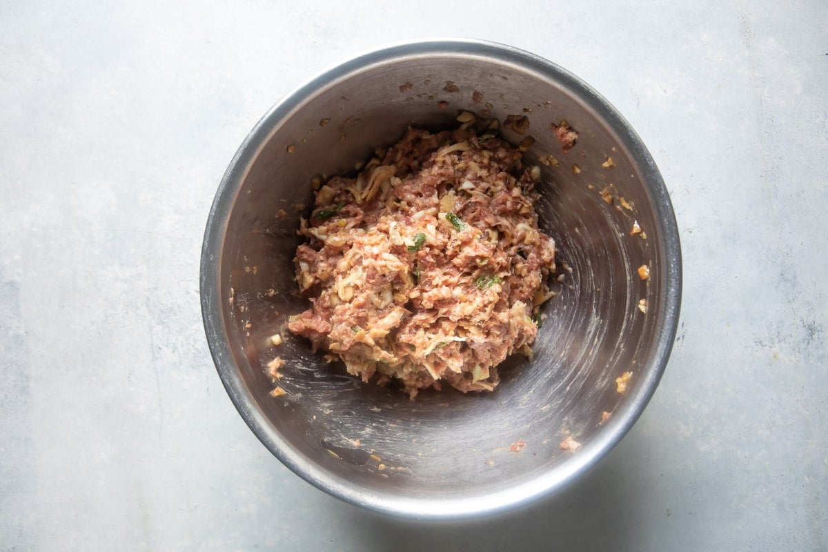 Raw pork potsticker filling in a bowl.