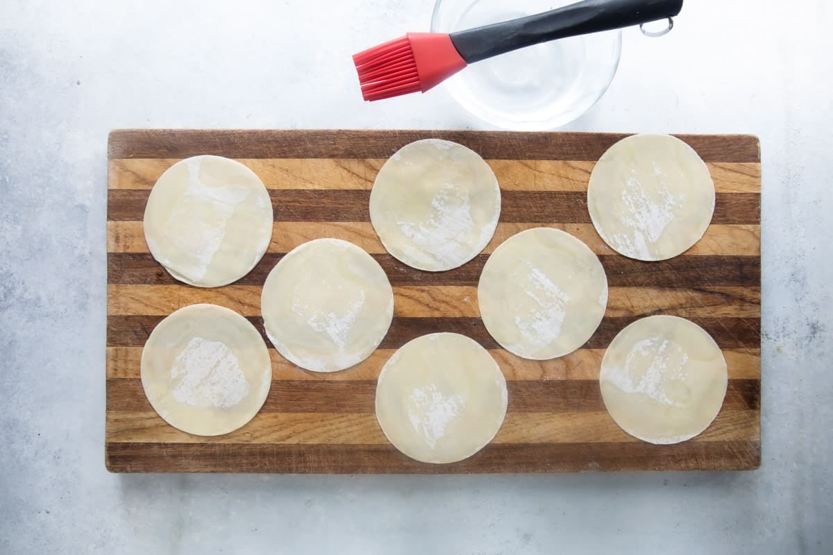 Brushing potsticker wrappers with water before filling.