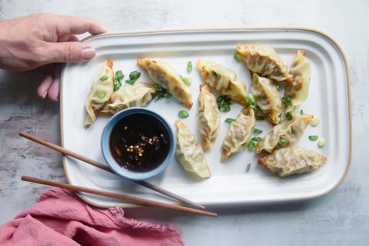 A platter of potstickers with ginger sauce.