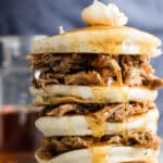 A stack of pulled pork pancakes with butter and whisky maple syrup on top.