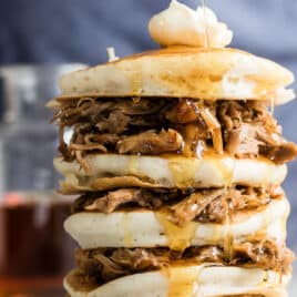 A stack of pulled pork pancakes with butter and whisky maple syrup on top.