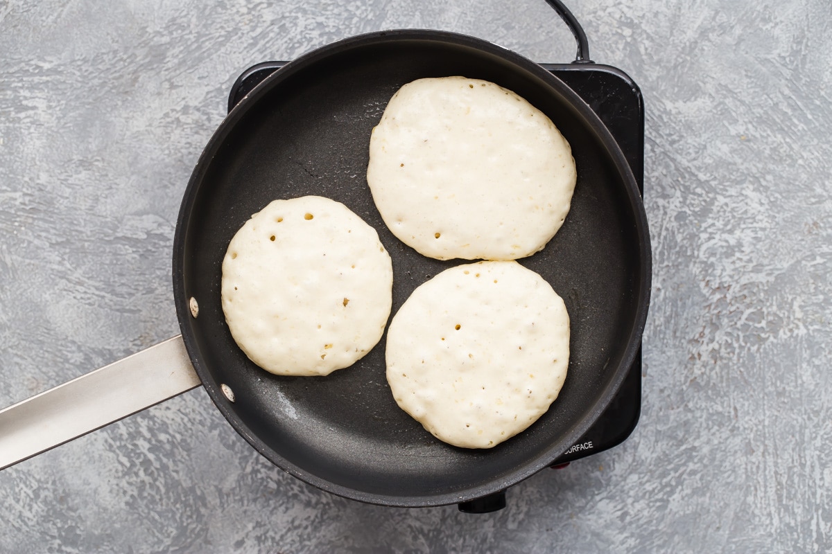 Pancakes cooking in a skillet.