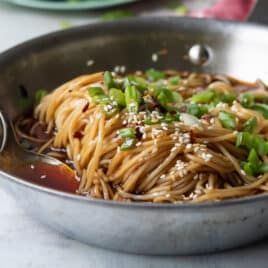 A silver skillet filled with teriyaki noodles.
