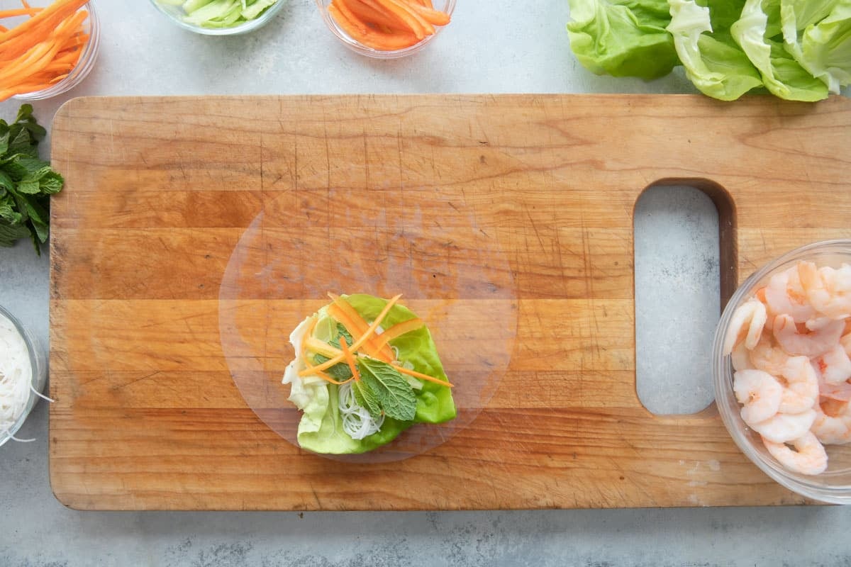 Assembling a Vietnamese spring roll with veggies.