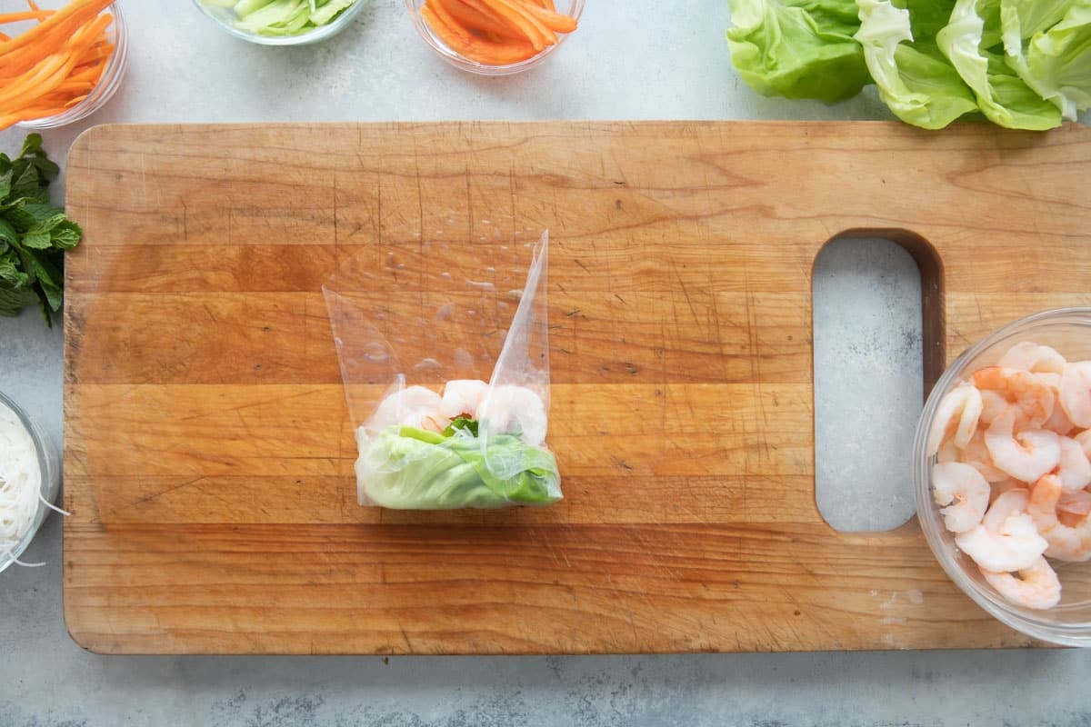 Assembling a Vietnamese spring roll with shrimp and veggies.