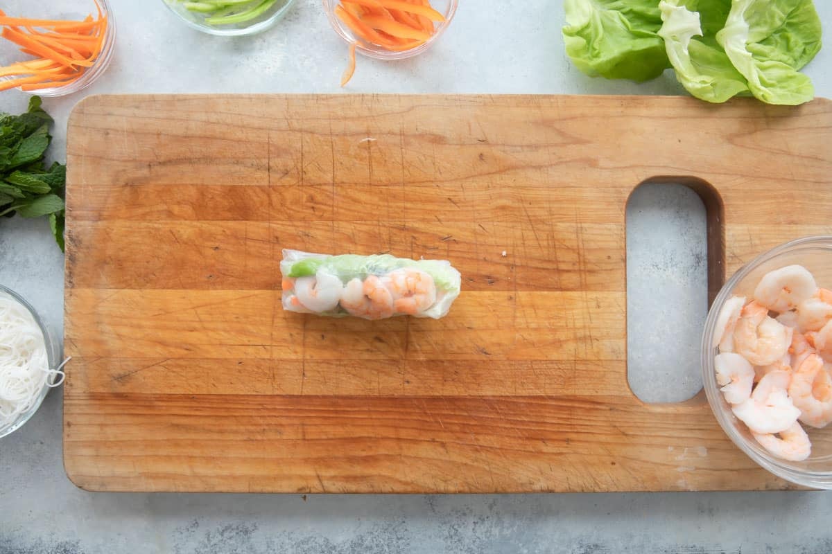 Assembling a Vietnamese spring roll with shrimp and veggies.