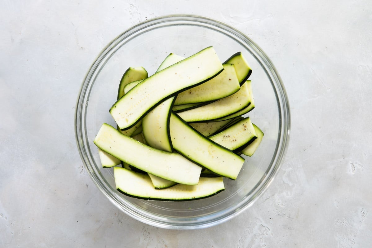 Zucchini strips in a clear bowl.