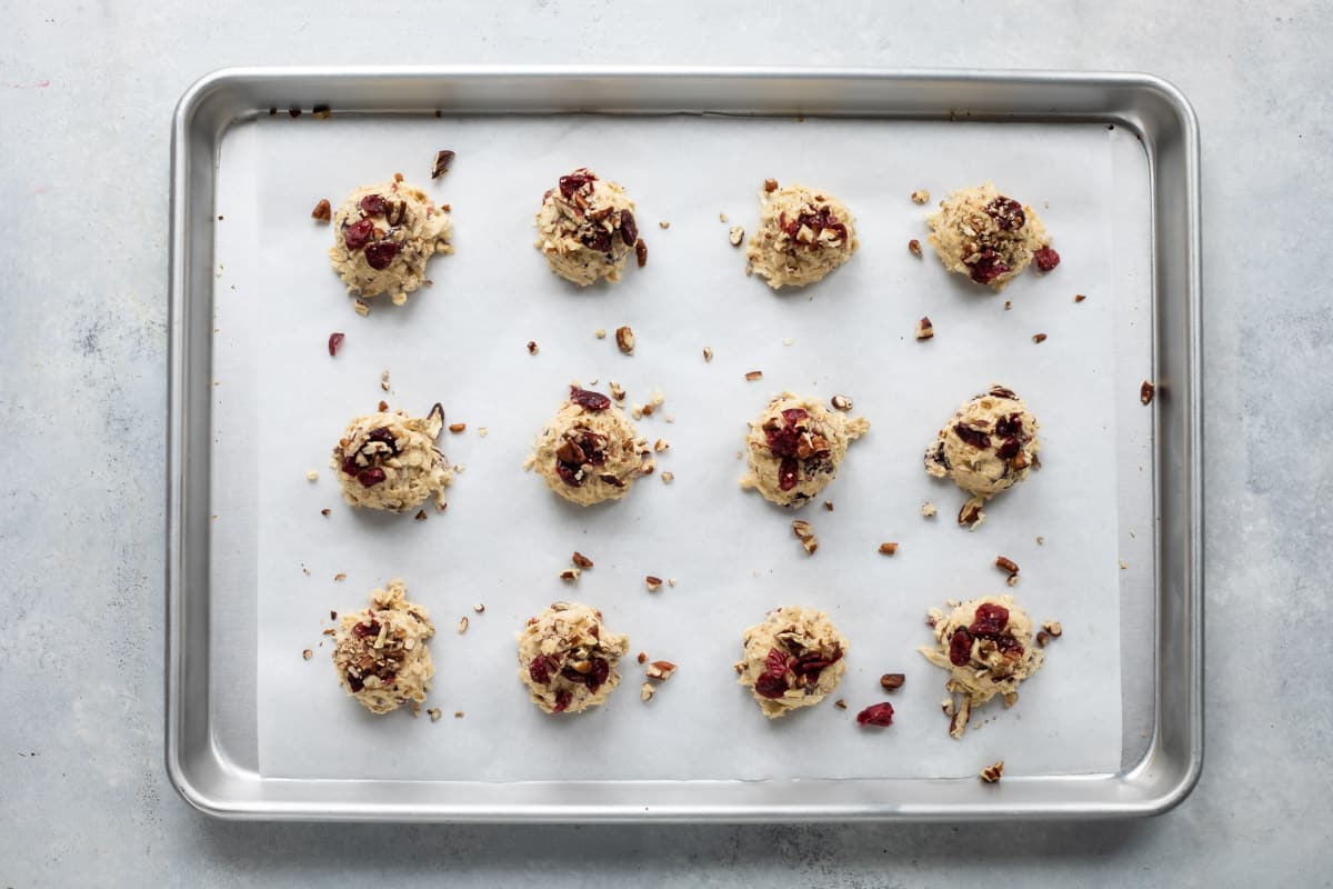 Twelve breakfast cookie dough balls on a parchment paper lined cookie sheet.