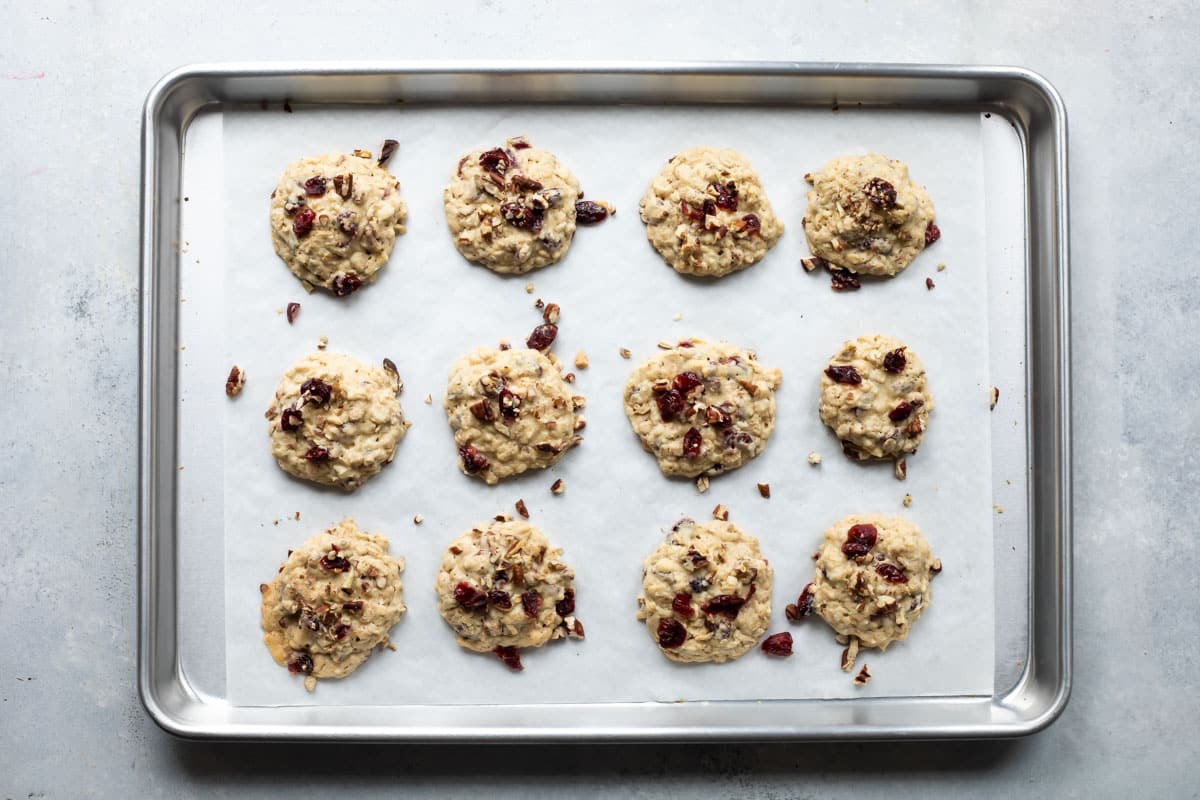 Twelve breakfast cookies on a parchment paper lined cookie sheet.