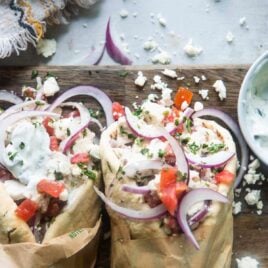 Two chicken gyros on a wooden cutting board.
