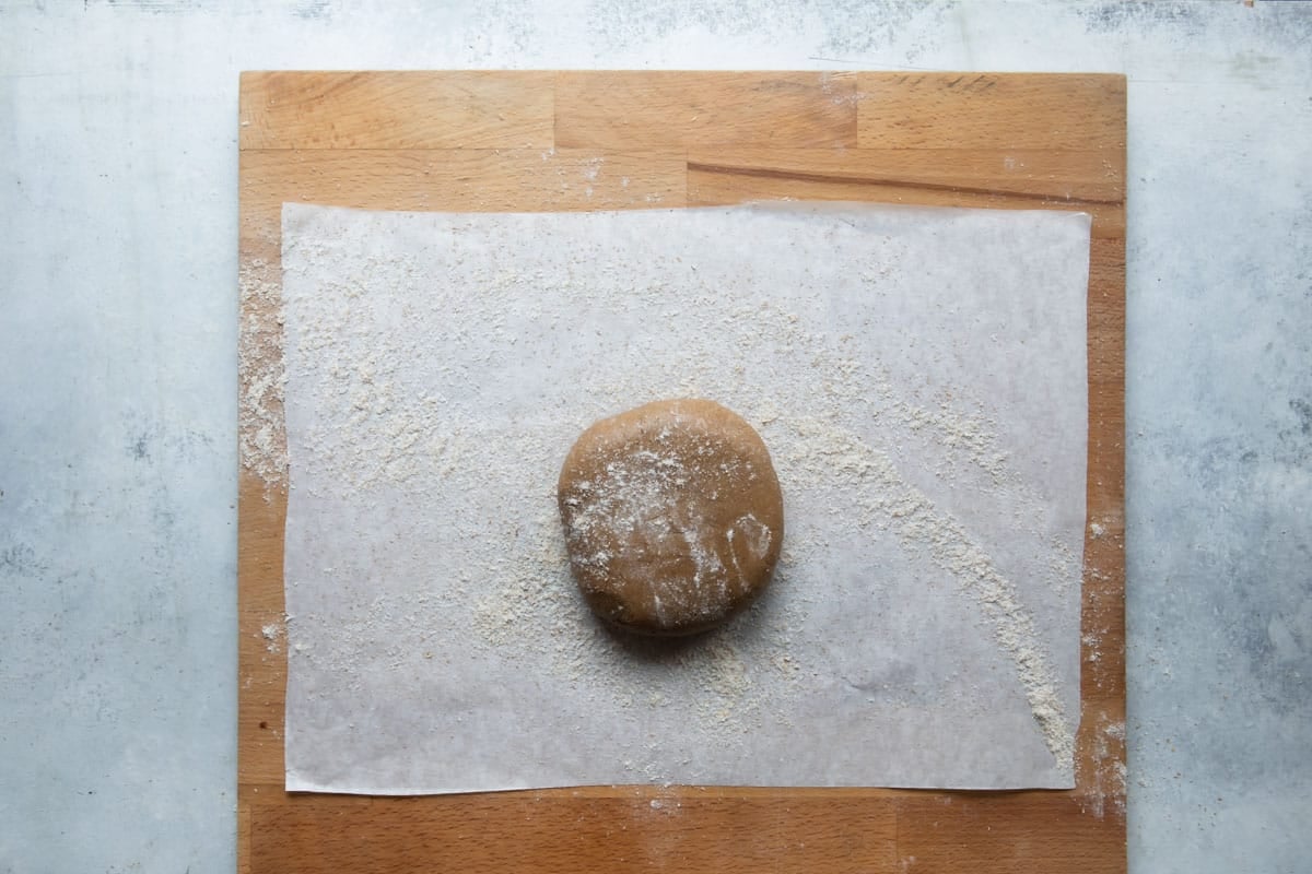 A square of graham cracker dough on parchment to be rolled out.