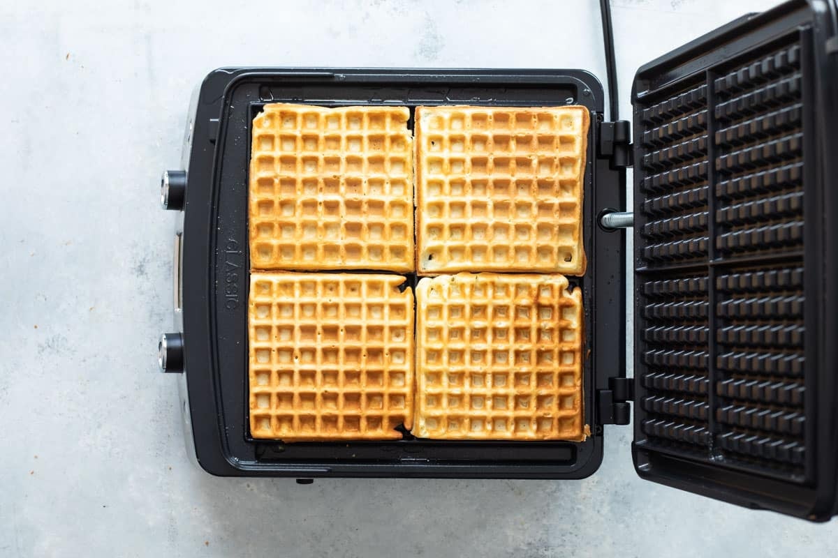 A waffle iron with four cooked waffles.
