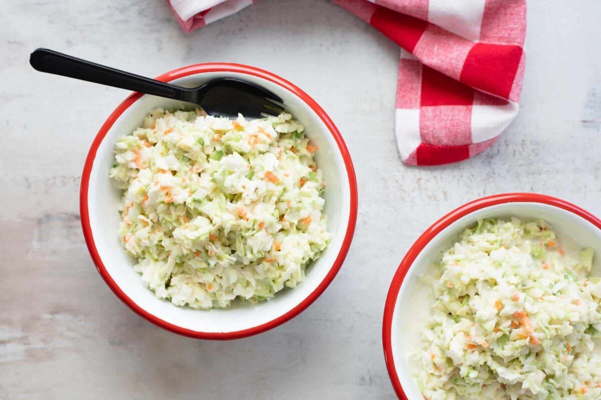 Two bowls of KFC coleslaw in white bowls with red rims.