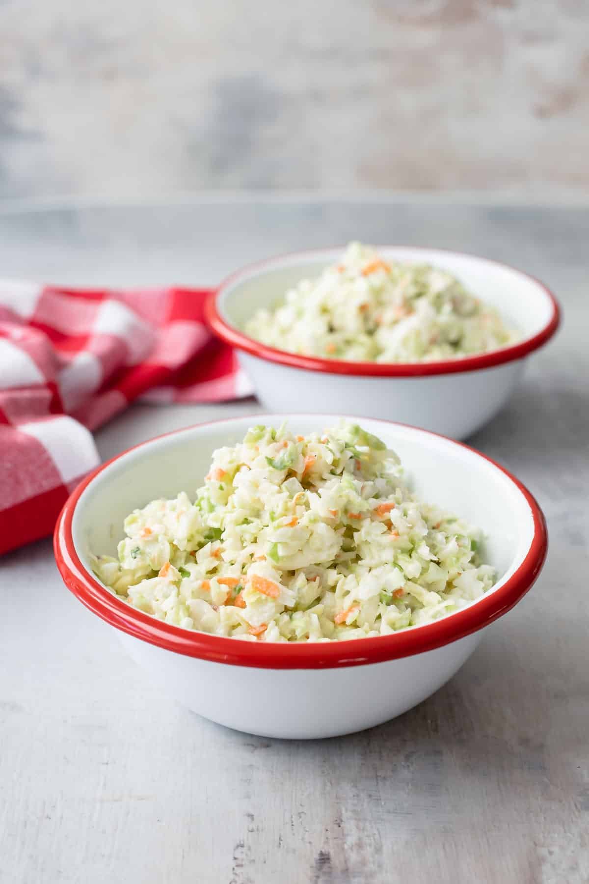 Two bowls of KFC coleslaw in white bowls with red rims.