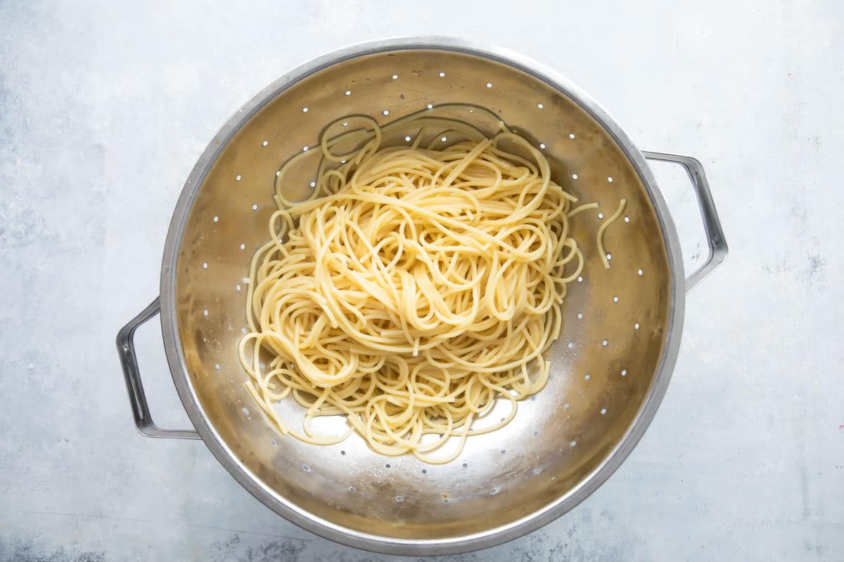A colander full of cooked spaghetti.