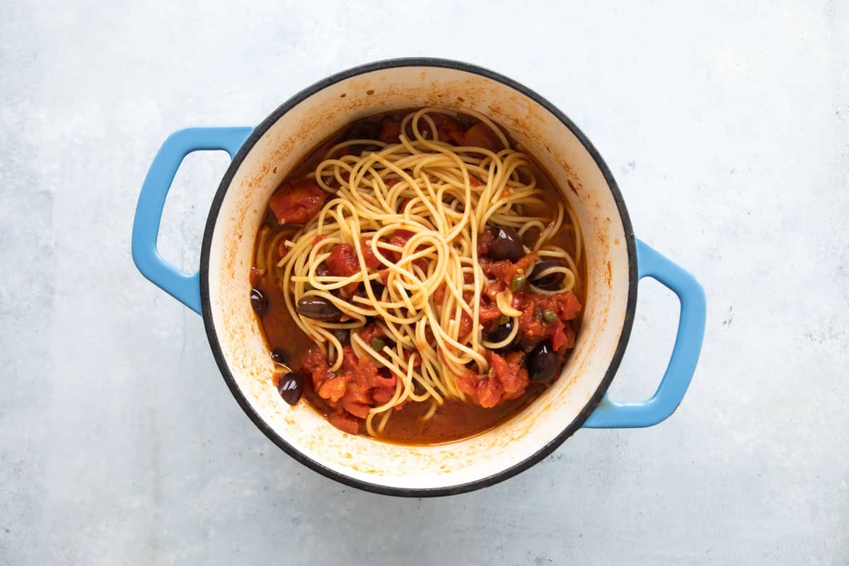 A Dutch oven full of pasta puttanesca.