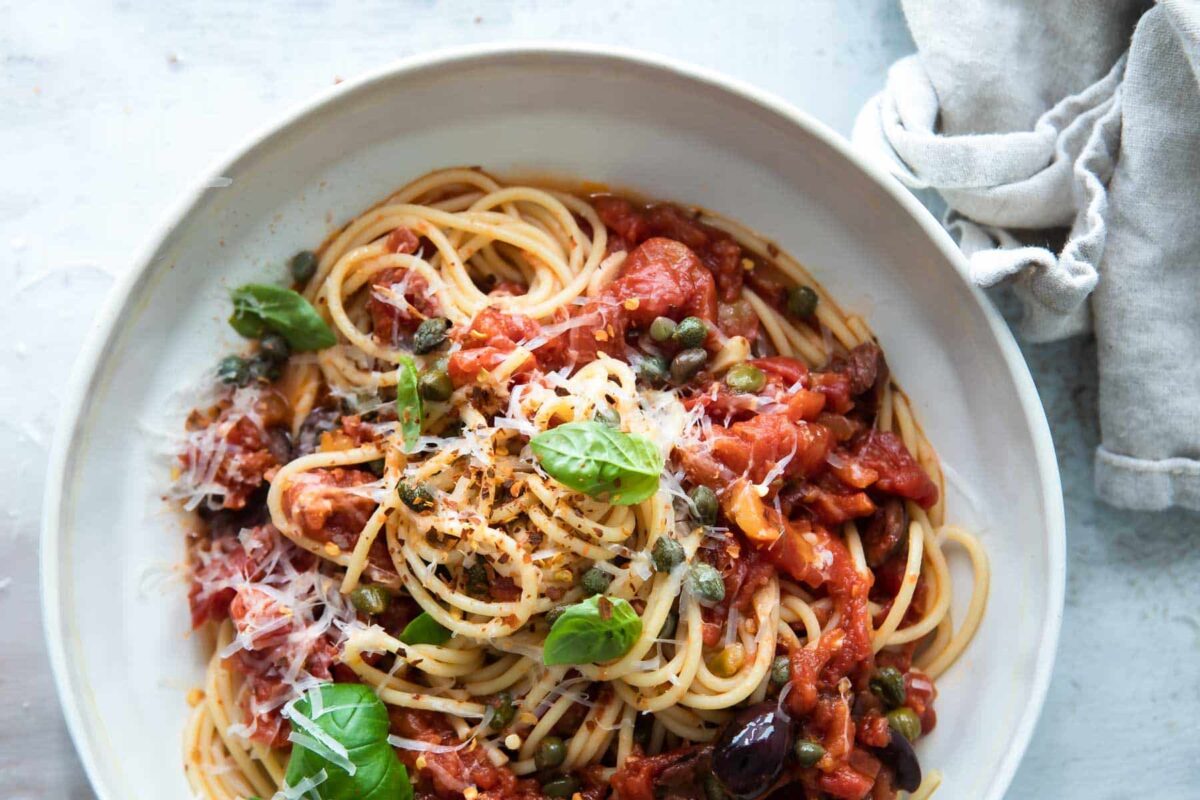 A serving platter full of pasta puttanesca.