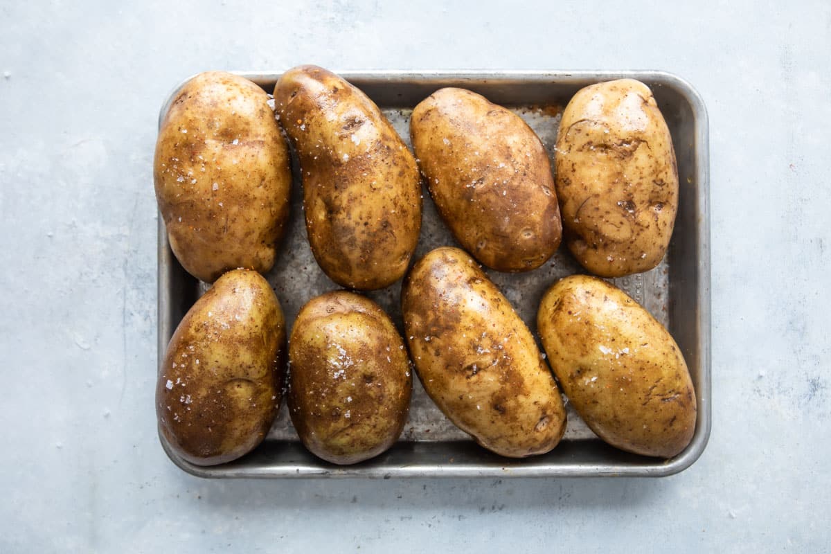 Potatoes with olive oil and salt on a baking sheet before being baked.