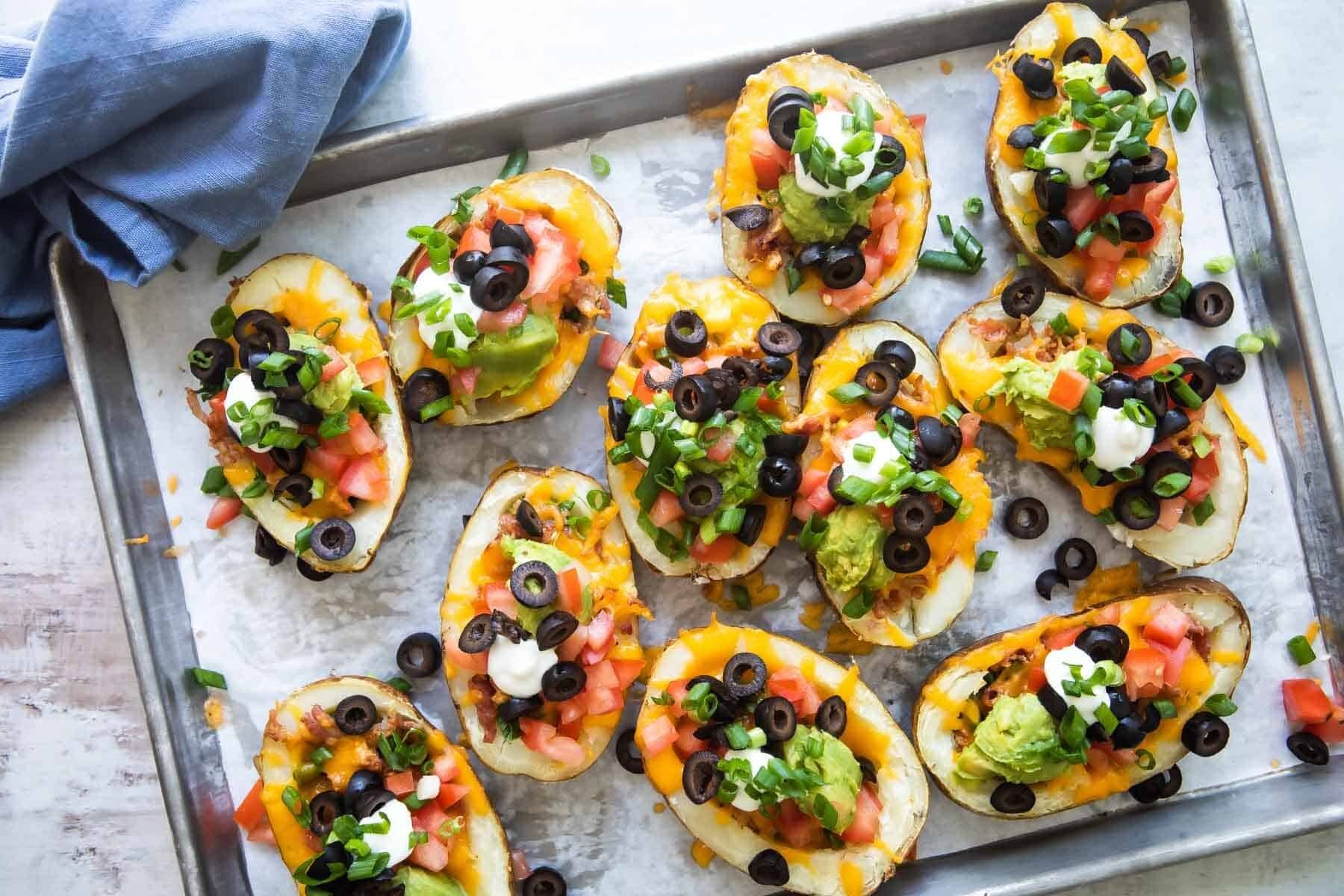 Potato skins on a parchment paper lined baking sheet.