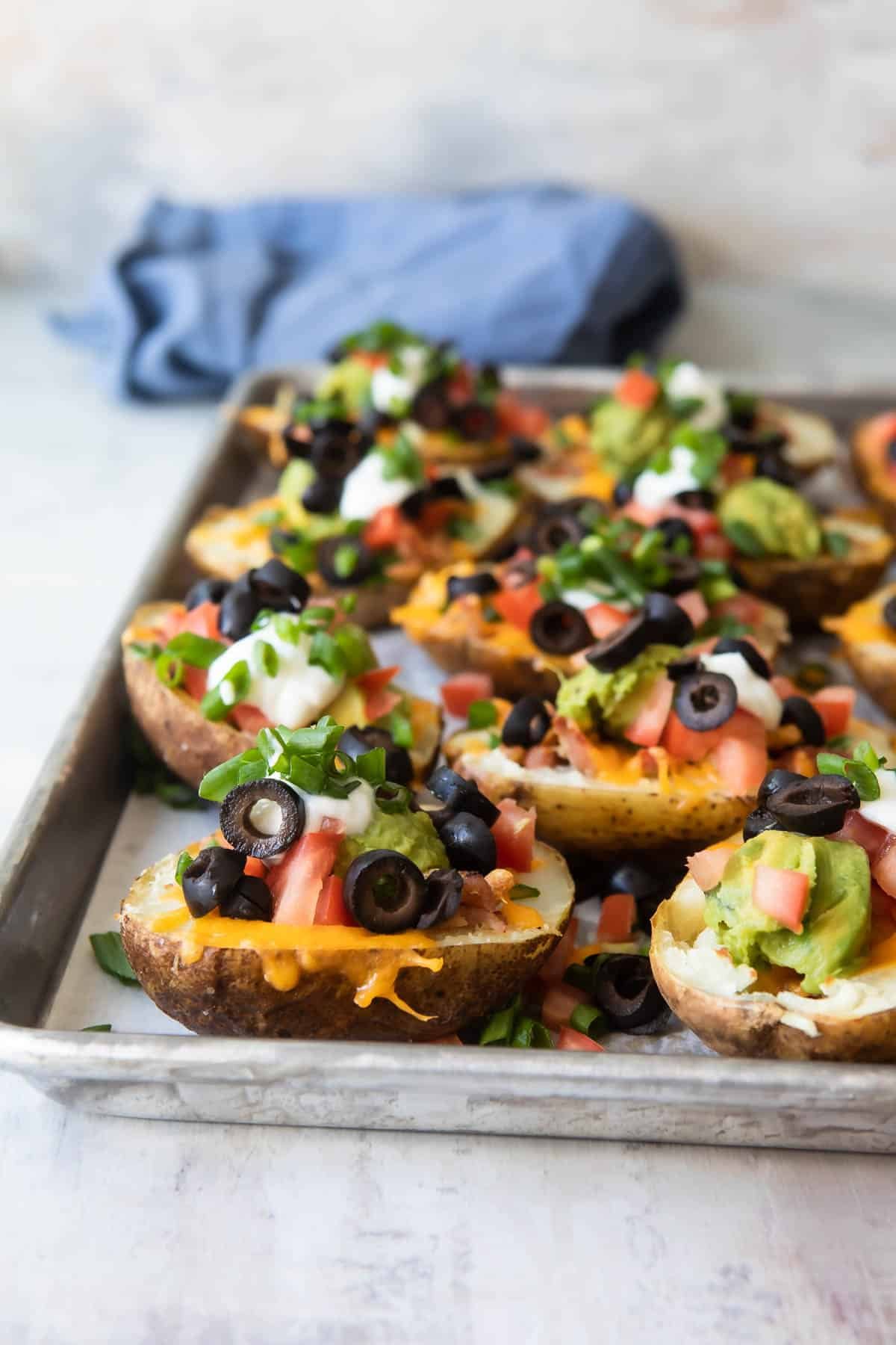 Potato skins on a parchment paper lined baking sheet.