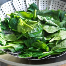A steamer basket filled with steamed spinach.