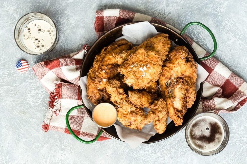 Fried chicken on a platter next to a beer and coleslaw.
