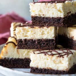 A stack of cheesecake brownies on a platter.