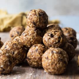 A stack of energy balls on a wooden cutting board.