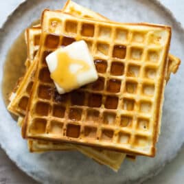 A stack of homemade waffles with syrup.