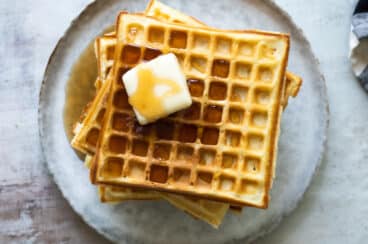 A stack of homemade waffles with syrup.