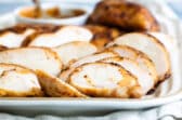 Smoked chicken breast slices on a white platter.